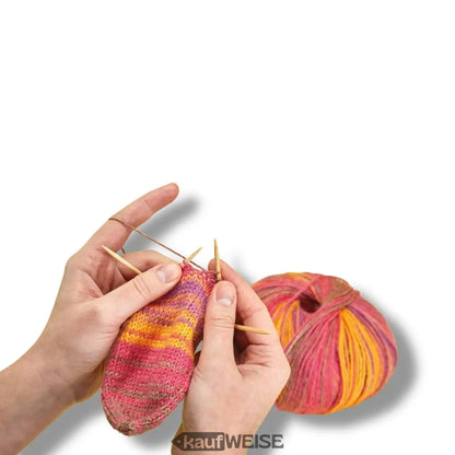 Handgestrickte Socke aus buntem Garn neben Addi 560-2 CraSyTrio BAMBOO Stricknadeln